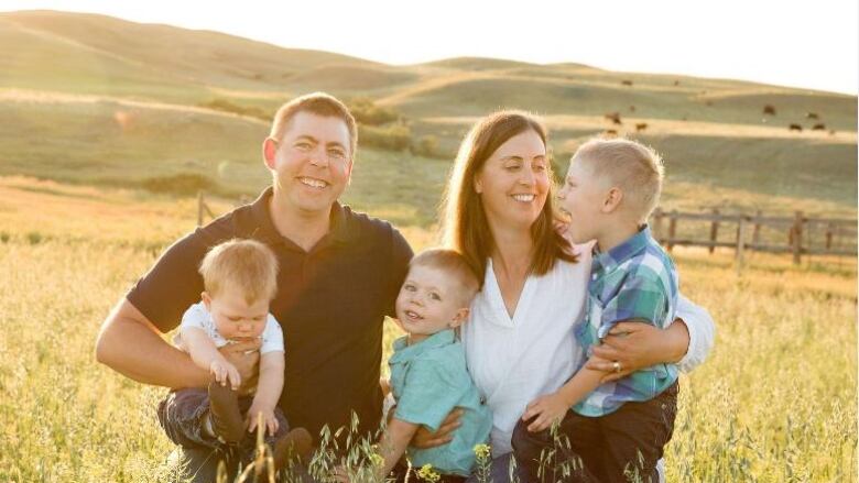 Cody Straza and Allison Squires with their family kneeling in a field.