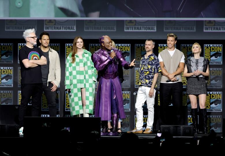 Eight men and women speak on stage.