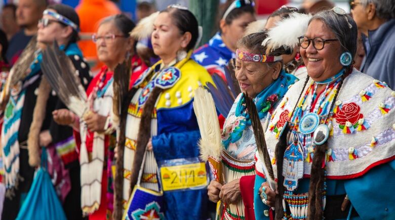 Indigenous women enter a powwow arbour on a First Nation.