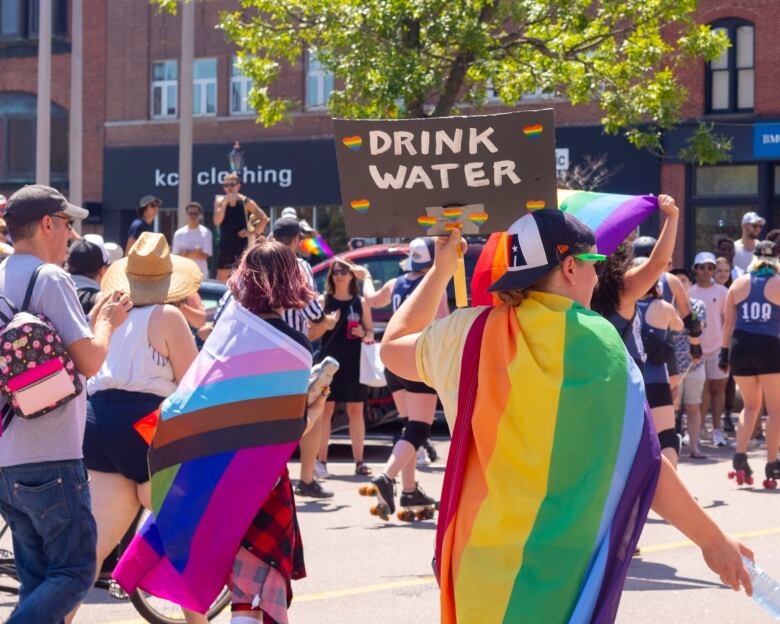 people walking in street at PEI Pride Parade draped in Pride flags