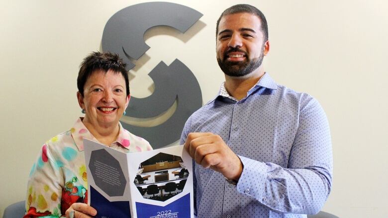 Two people hold a copy of a municipal election platform.