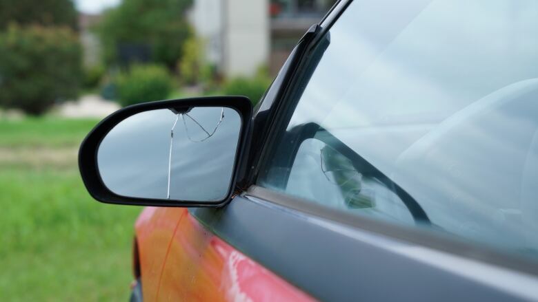 A close-up photo shows a broken side mirror on a car.