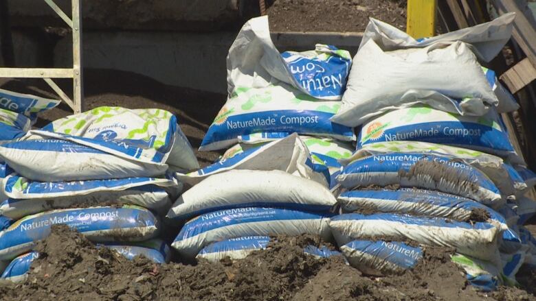 Bags of compost sit on the ground.