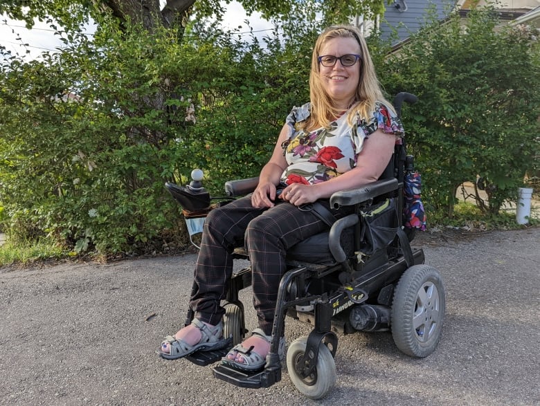 A smiling woman sits in a wheelchair