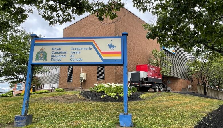 Exterior of the Codiac Regional RCMP building in Moncton showing a sign for the building and an emergency backup generator beside the wall. 