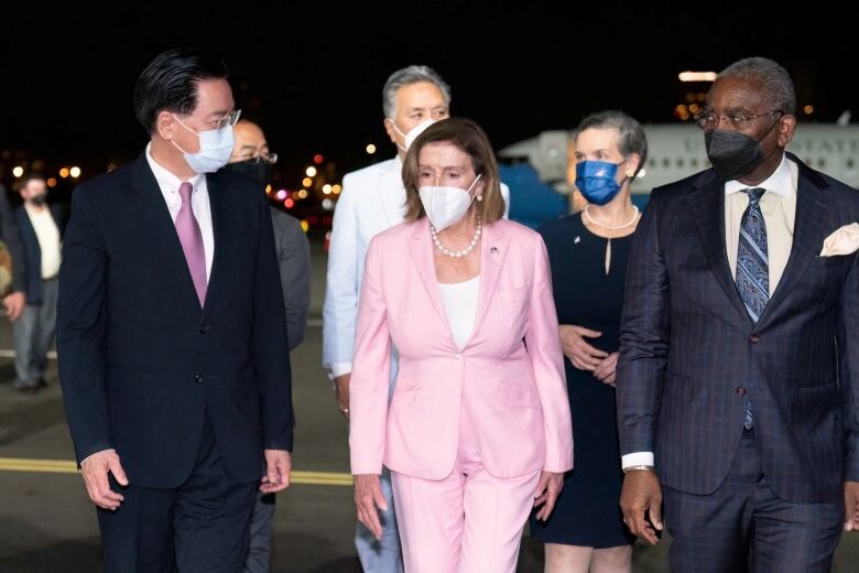 Several people are seen walking on the tarmac of an airport.