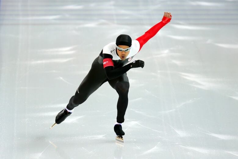 A man is skating, directly facing the camera. His opposite arm and leg are outstretched as he is mid-skate. 