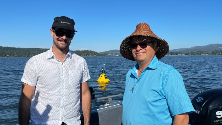 Two men stand at the front of a boat on the ocean.