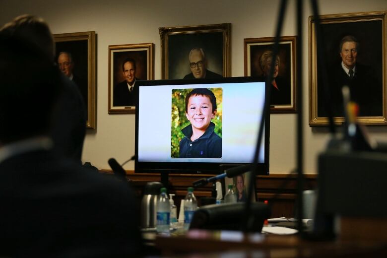 A photo of a young boy is seen on a TV screen in a darkened courtroom.