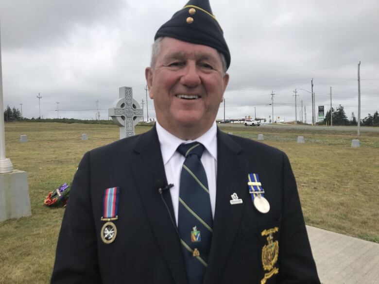 Leo O'Brien stands in a field of grass dressed in a ceremonial military uniform with medals. 