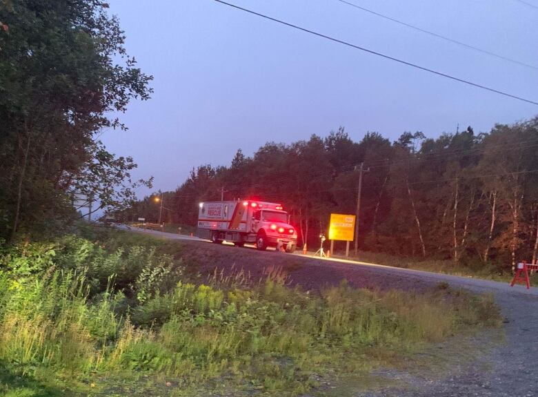 A search and rescue truck with red lights blocks a road.