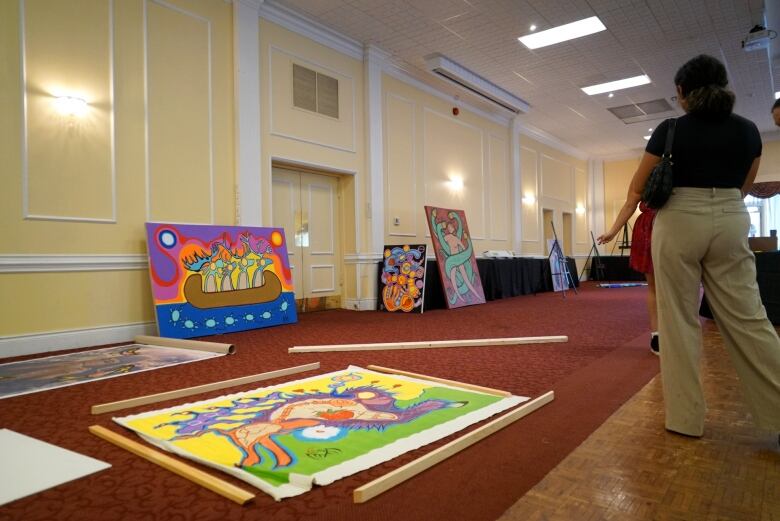 Canvases of Indigenous art sit on a carpeted floor waiting to be mounted and put on display.