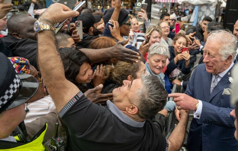 People in a crowd take pictures of a man.