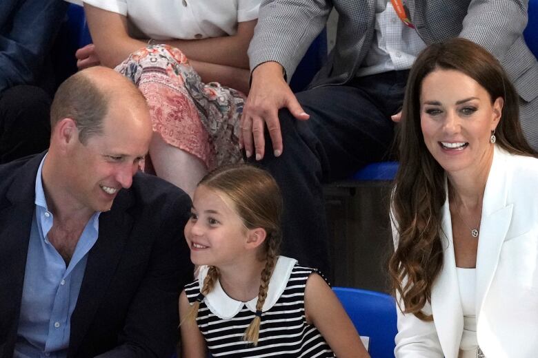 A child sits between two adults watching a sports competition.