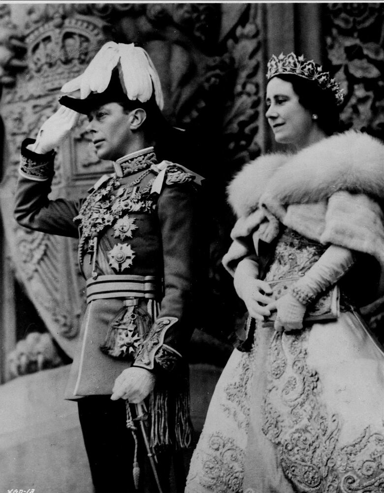 Two people stand on the steps of a large building.