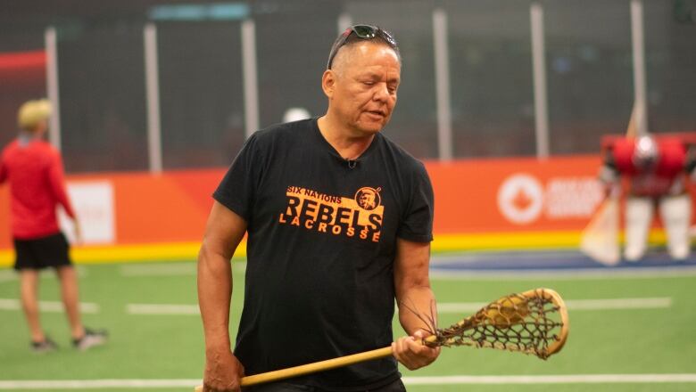 A man holding a wooden lacrosse stick.