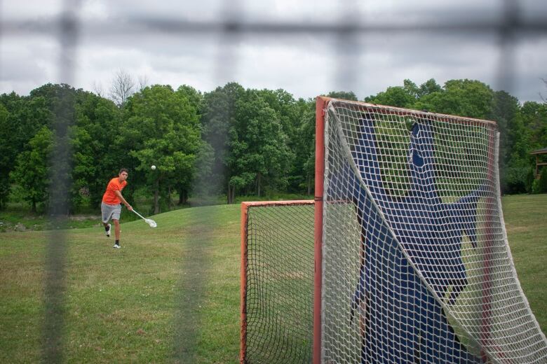 A boy shoots a ball at a net.