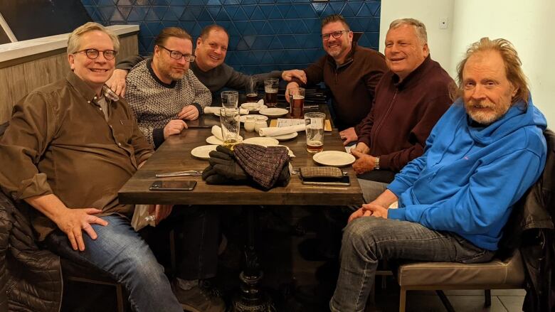 Six men sit at a table.