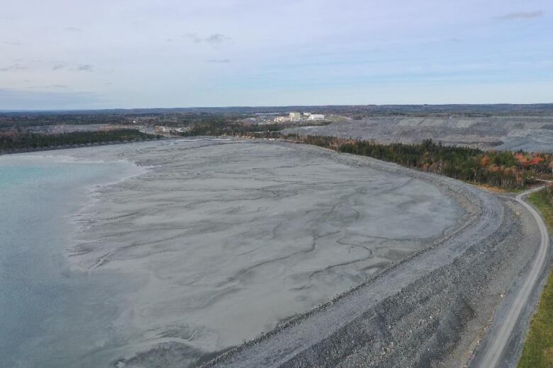 An aerial view shows a huge rock wall containing what looks like water and sediment.