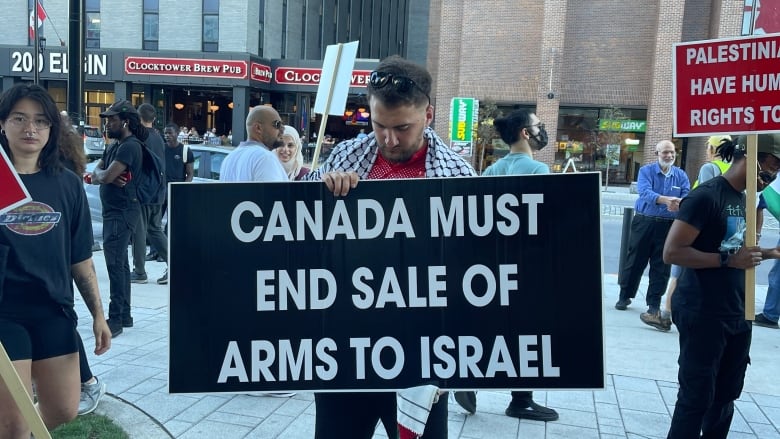 A man holds a sign reading 