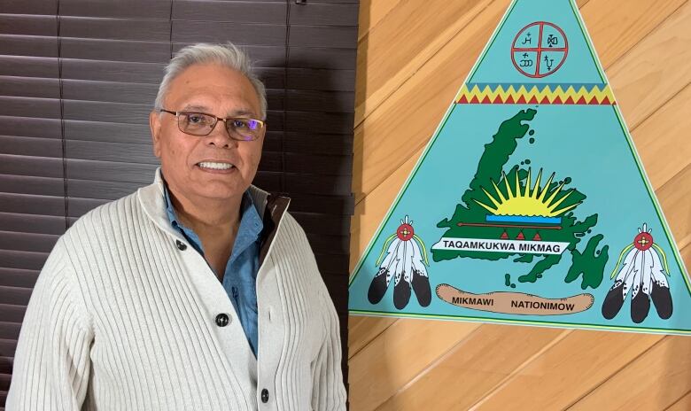 Chief Joe stands next to the Miawpukek First Nation emblem.