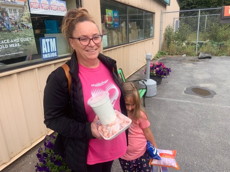 A person holds chicken wings and flour outside a grocery story. 