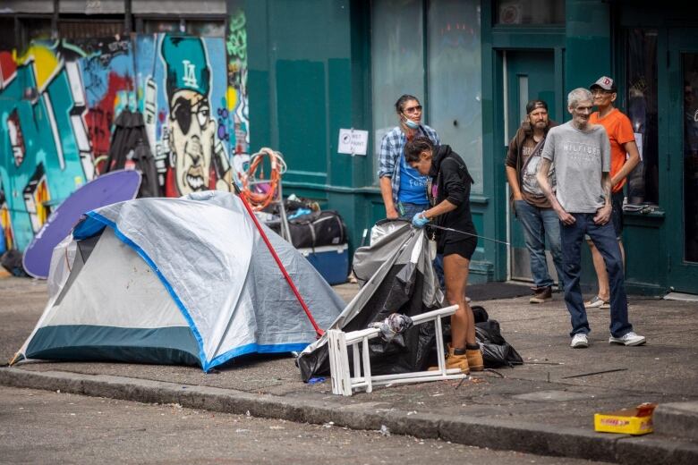 Tents are pictured being dismantled on a street. 