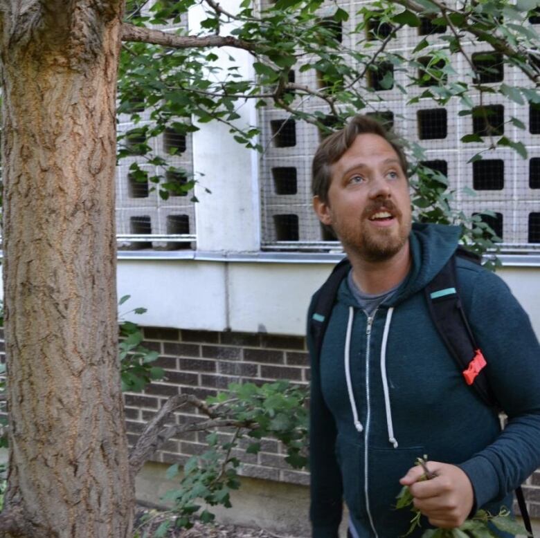 A man standing beside a tree