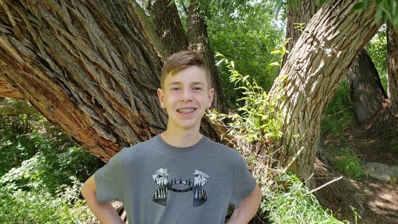 A teenage boy standing in front a tree