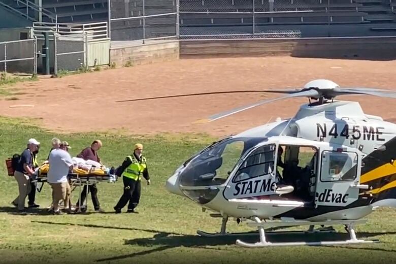 A patient on a stretcher is taken to a helicopter.