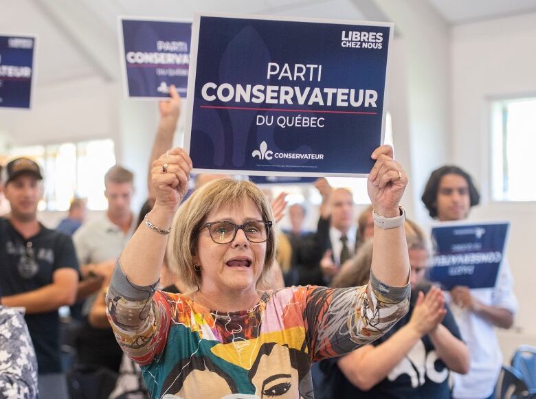 A woman is holding a campaign sign.