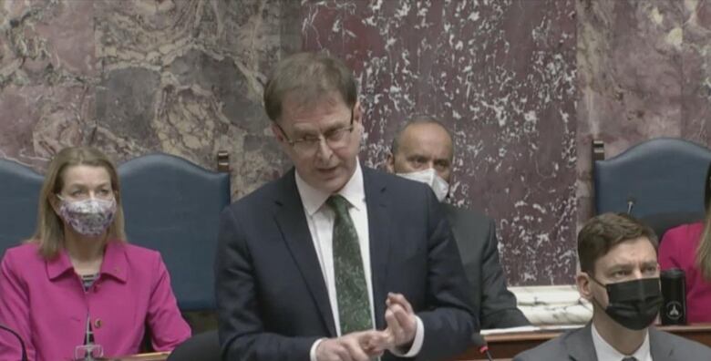 Adrian Dix gestures among colleagues on the floor of the legislature.