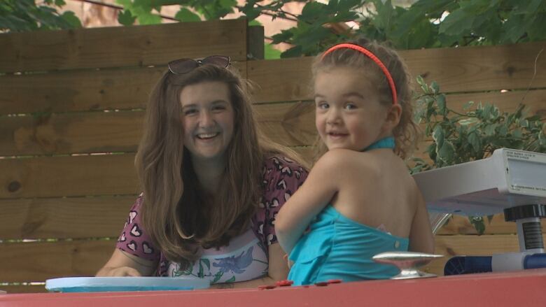 Olivia Kendall is seen smiling as her daughter, Adele, sits in the cherry red pool-boat.