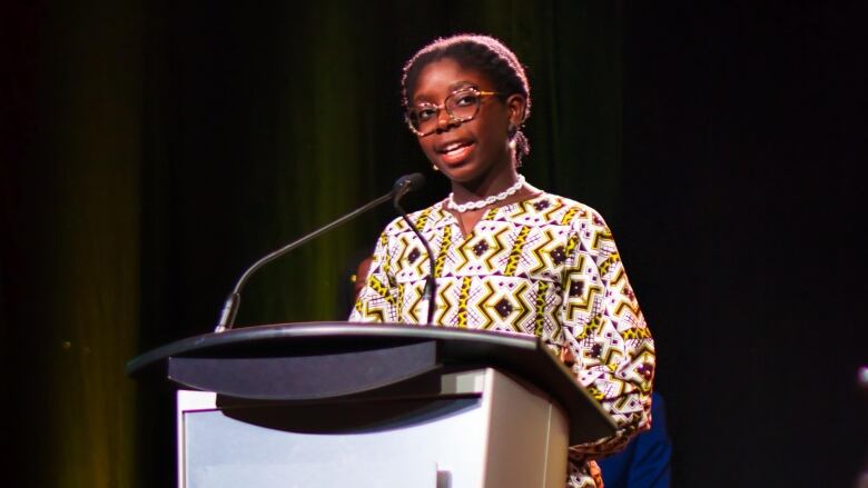 Black teen woman speaking at a podium