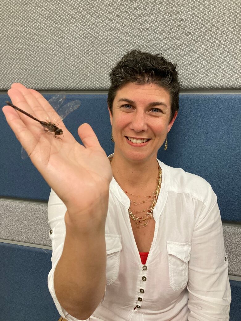 Jennifer Babin-Fenske holds a dragonfly in her right hand.