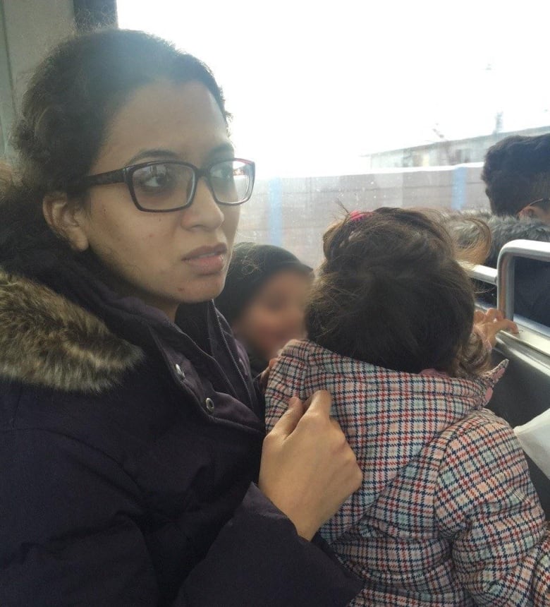 A woman sits with two children on a train car seat.