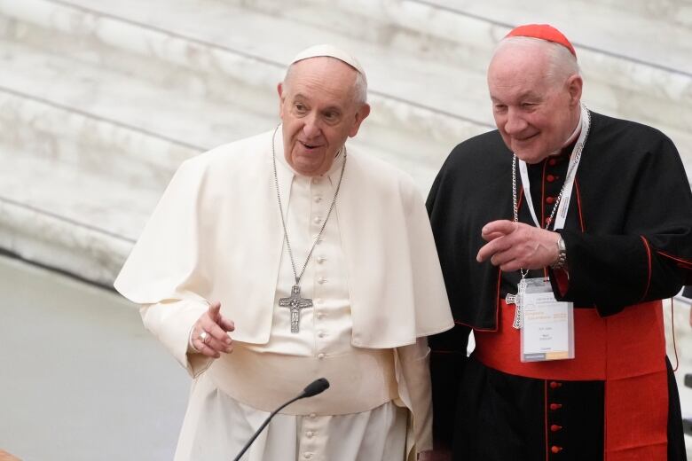 Pope in white on left, cardinal in black and red on right.