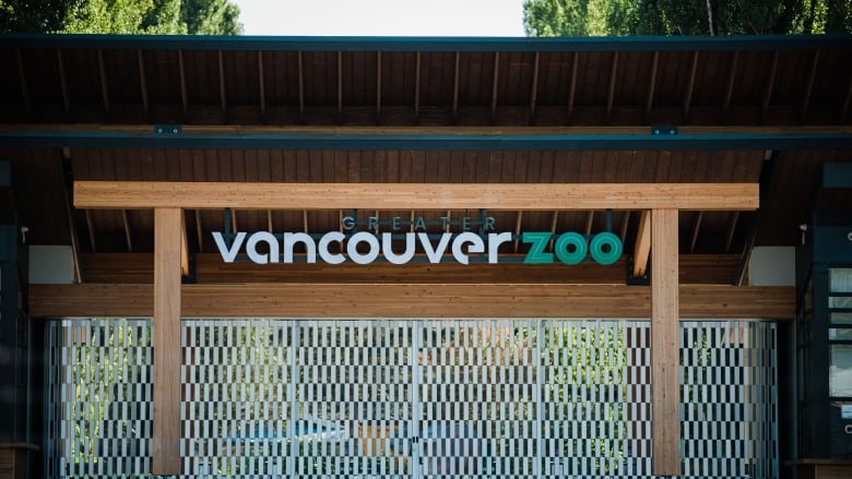 A sign saying Greater Vancouver Zoo over wooden framing and security barriers at the entrance to the zoo.