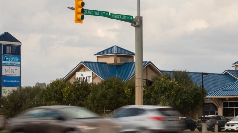 Cars drive through an intersection while it rains.