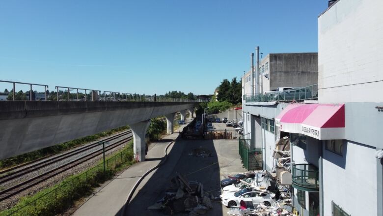 Rail tracks alongside are seen alongside a block of industrial buildings.