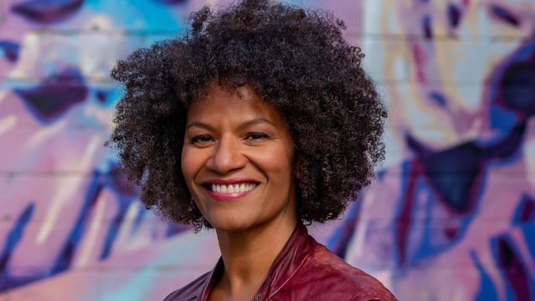 Woman with black curly hair in front of a mural.