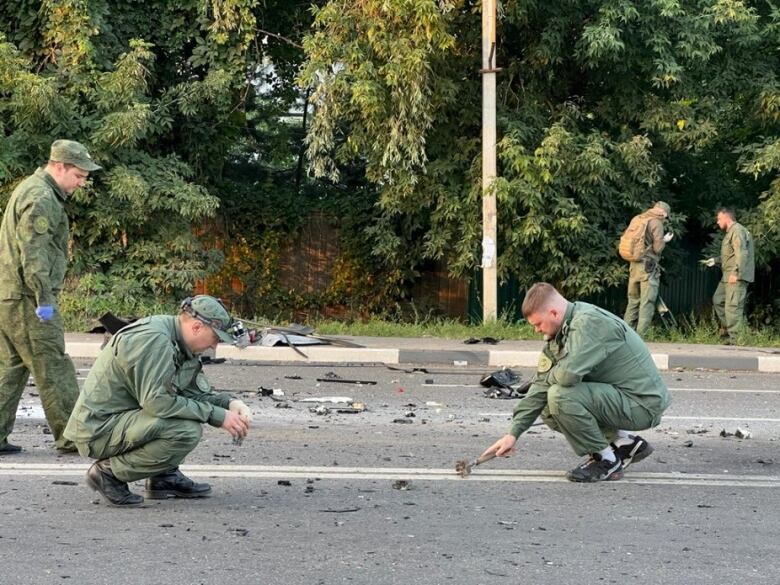 Men pick at debris on the road.