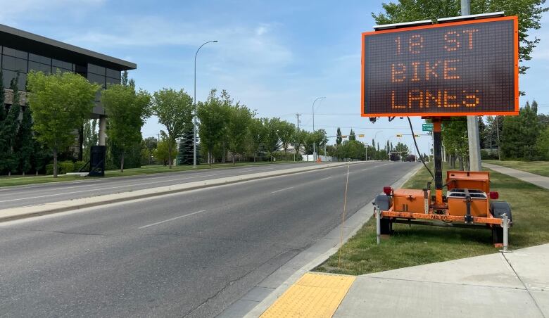 A sign along a road that reads 18 Street bike lanes