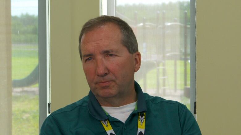 A man is seen sitting next to a window, talking to a reporter.