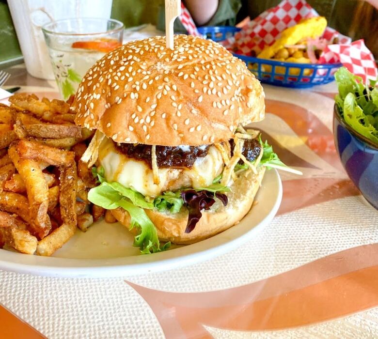 A burger and fries on a plate being eaten at a restaurant.