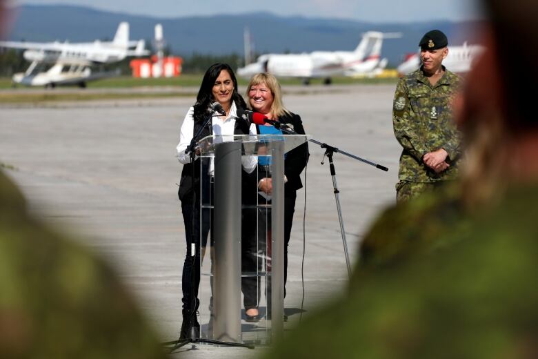 Defence Minister Anita Anand stands on the tarmac at 5 Wing Goose Bay with Canadian Armed Forces members in the foreground. 