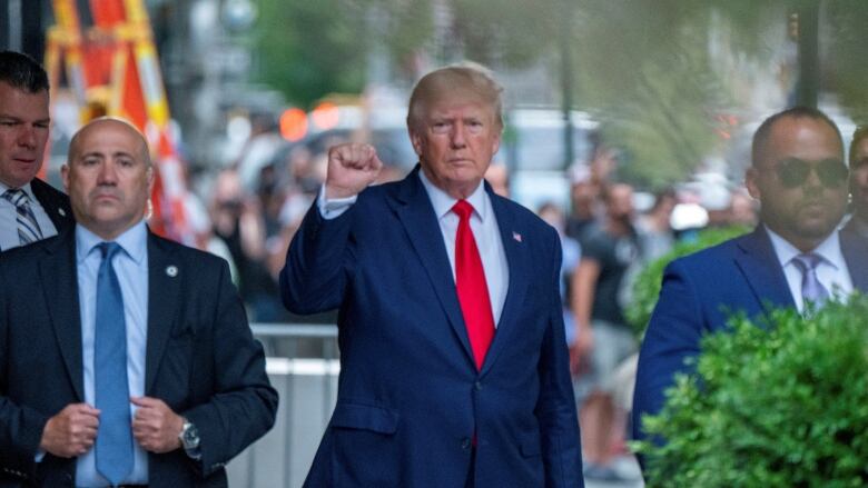 A man on a city street gestures with his fist.