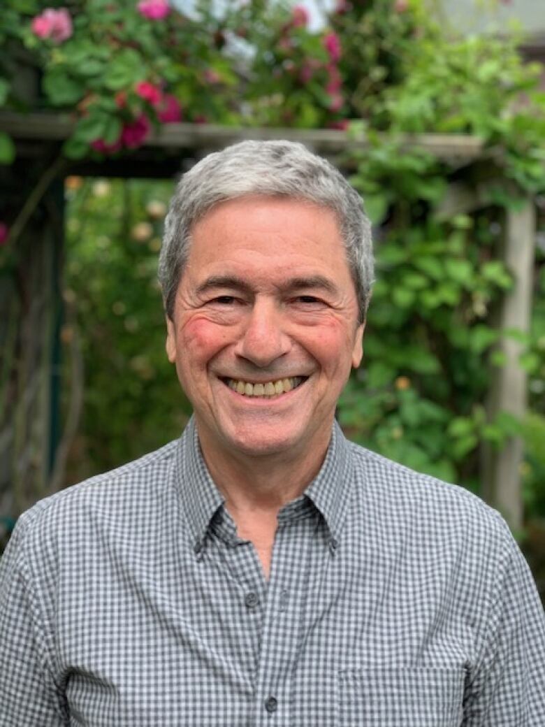 A man standing outside smiles while looking directly into the camera.