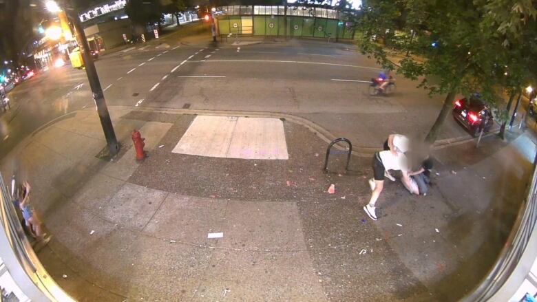 CCTV footage shows three men beating on a man who is lying on a pavement. Two women are visible to the left.