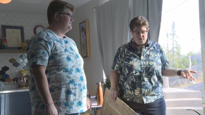 Two women stand near a window in their home, the day after a bear had broken into it.